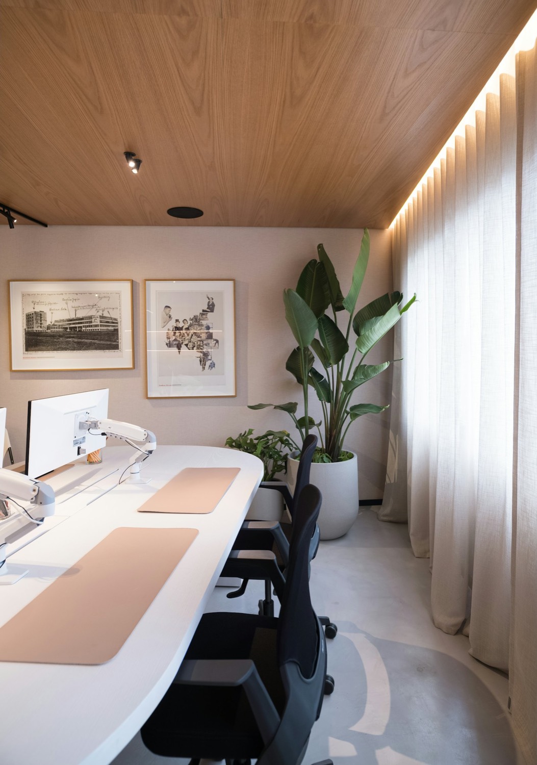 A calm workspace with a long desk and daylight through curtains.
