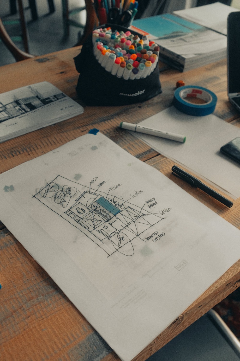 An interface layout sketched in pen on paper beside a set of marker pens.